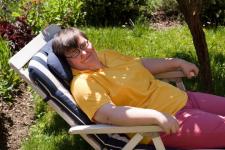 photo of man sitting in a lawn chair outside under a tree